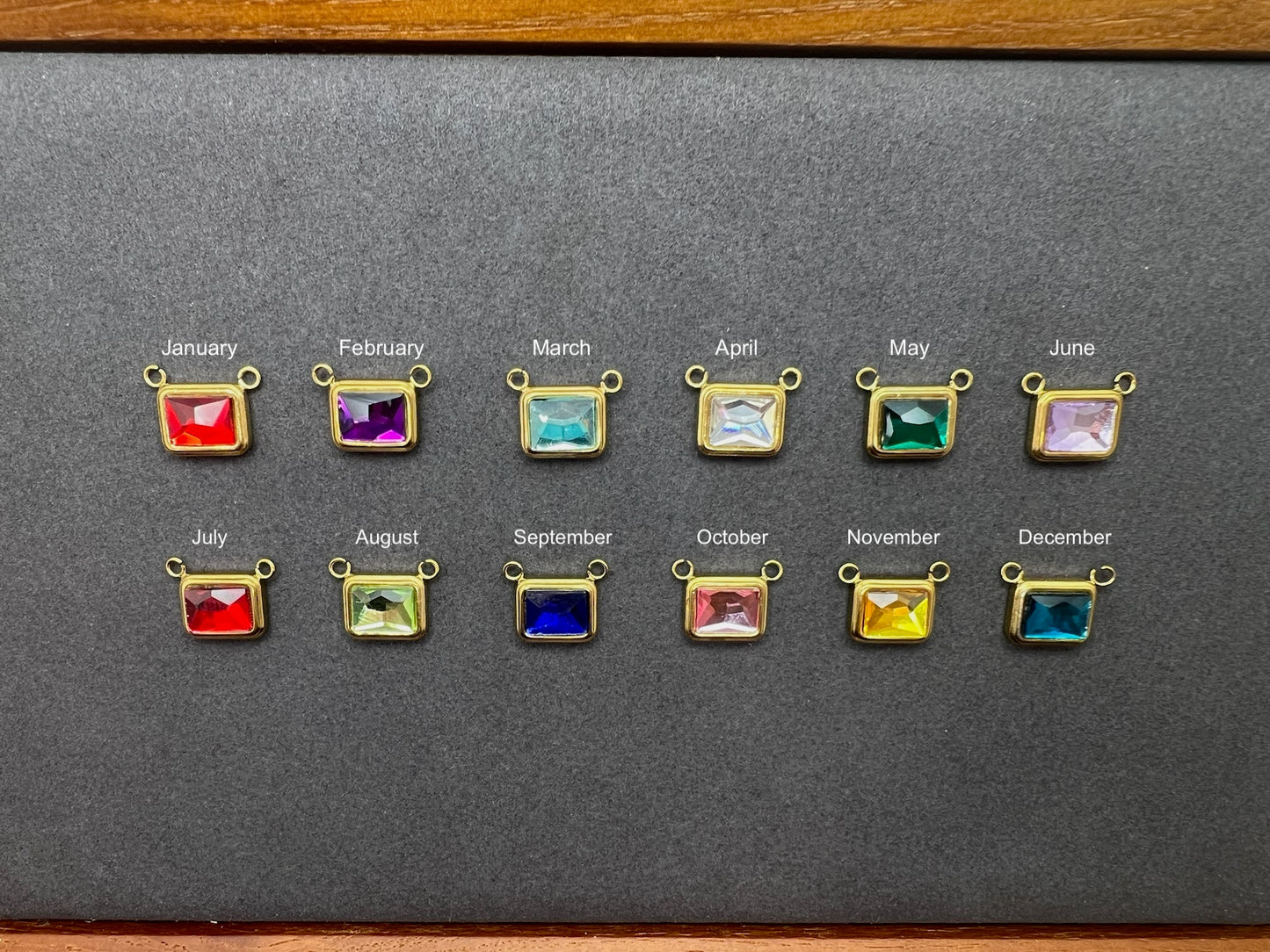 Set of gemstone earrings with colored stones for each month on a gray background