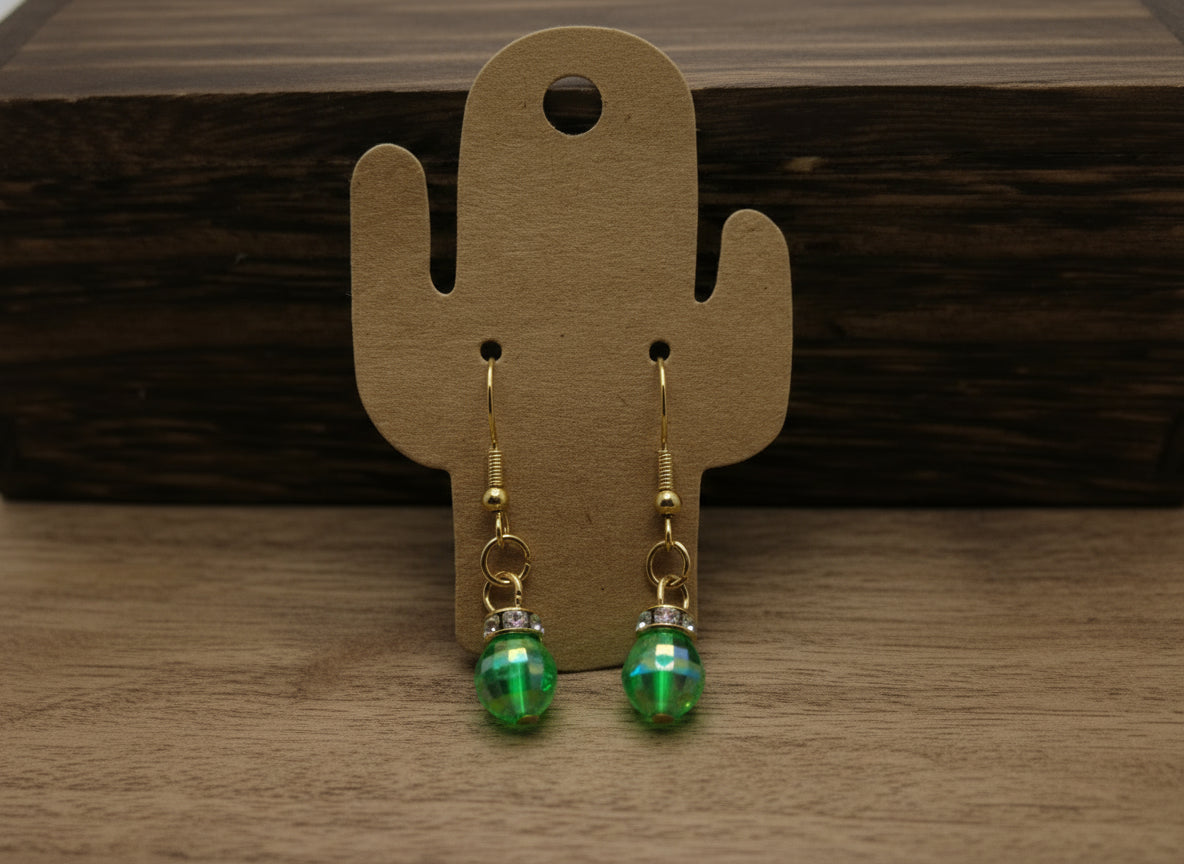 Green beaded earrings on a cactus-shaped card against a wooden background