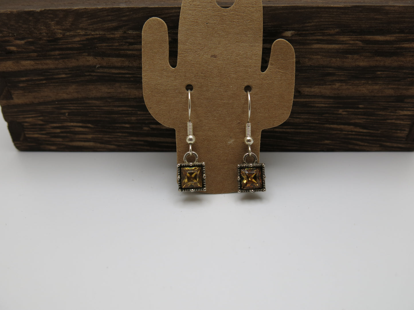 Pair of earrings on a cactus-shaped card against a wooden background
