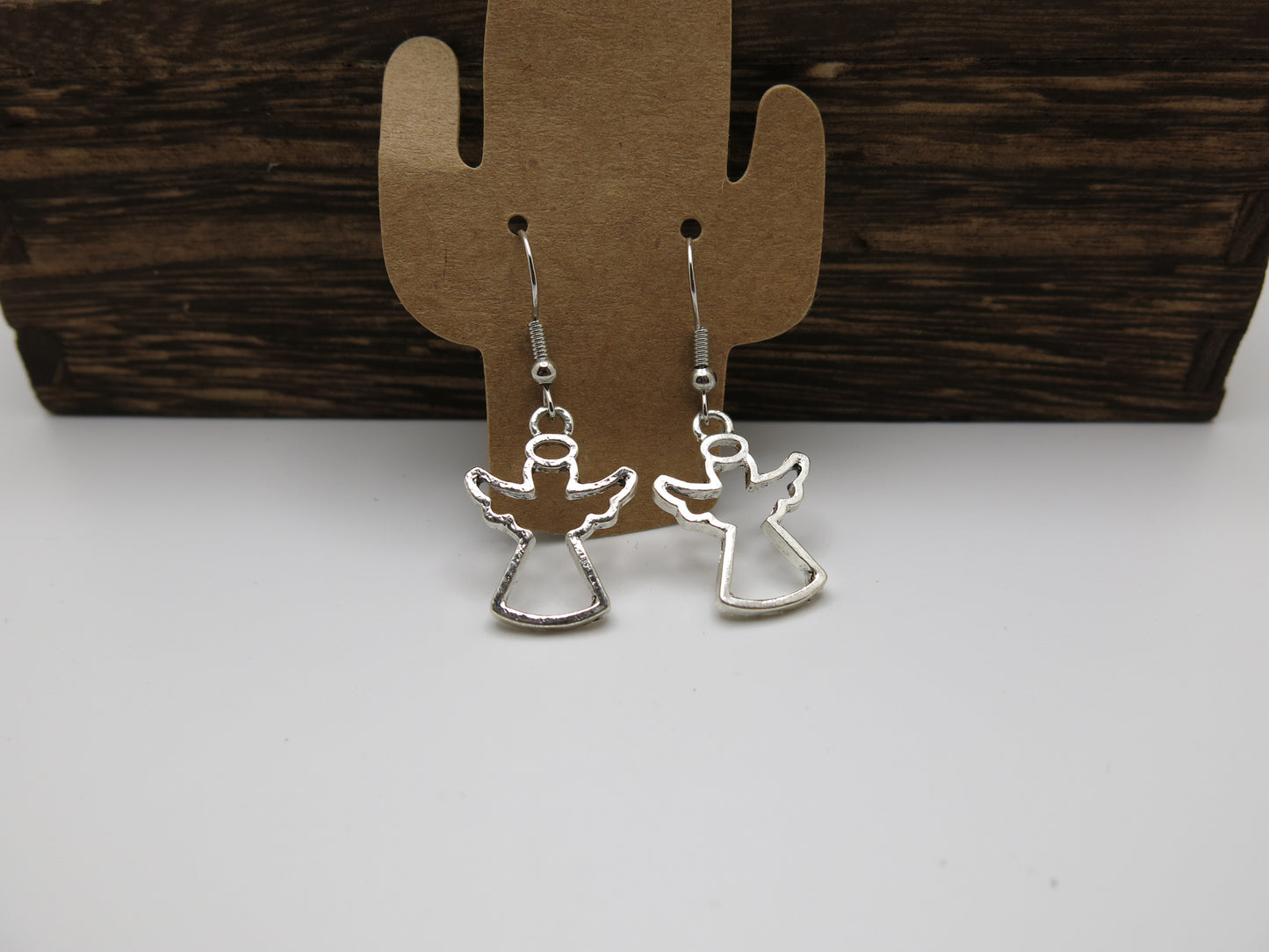Silver angel-shaped earrings on a wooden cactus-shaped stand.