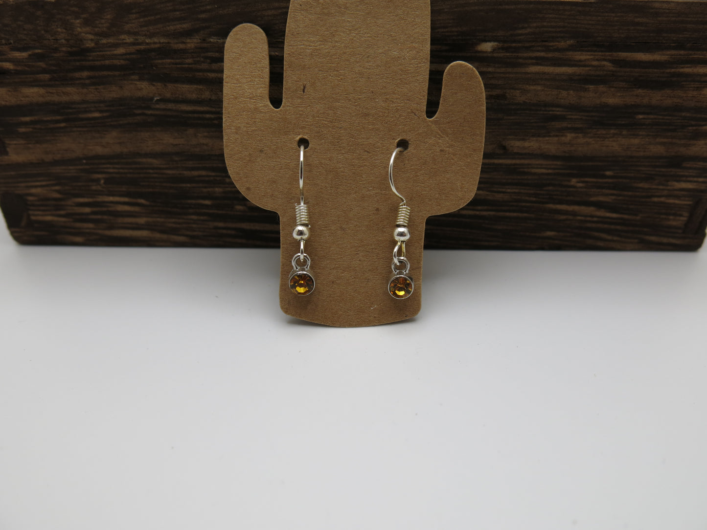Pair of earrings on a cactus-shaped wooden stand against a wooden background