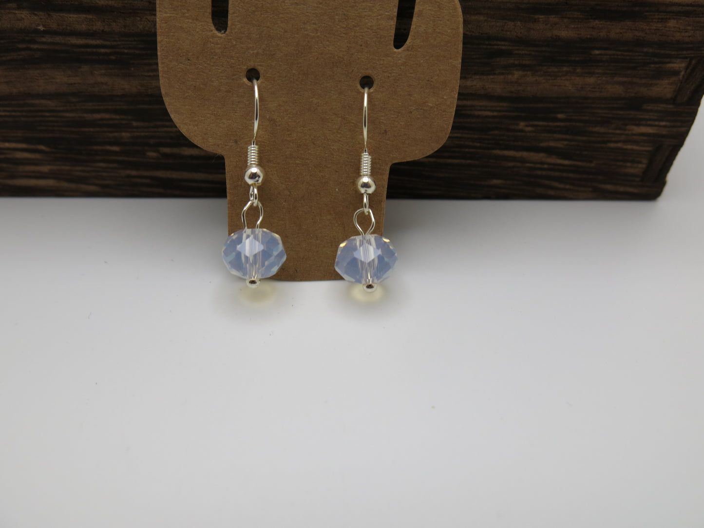 Pair of earrings with crystal beads on a brown earring card against a white background