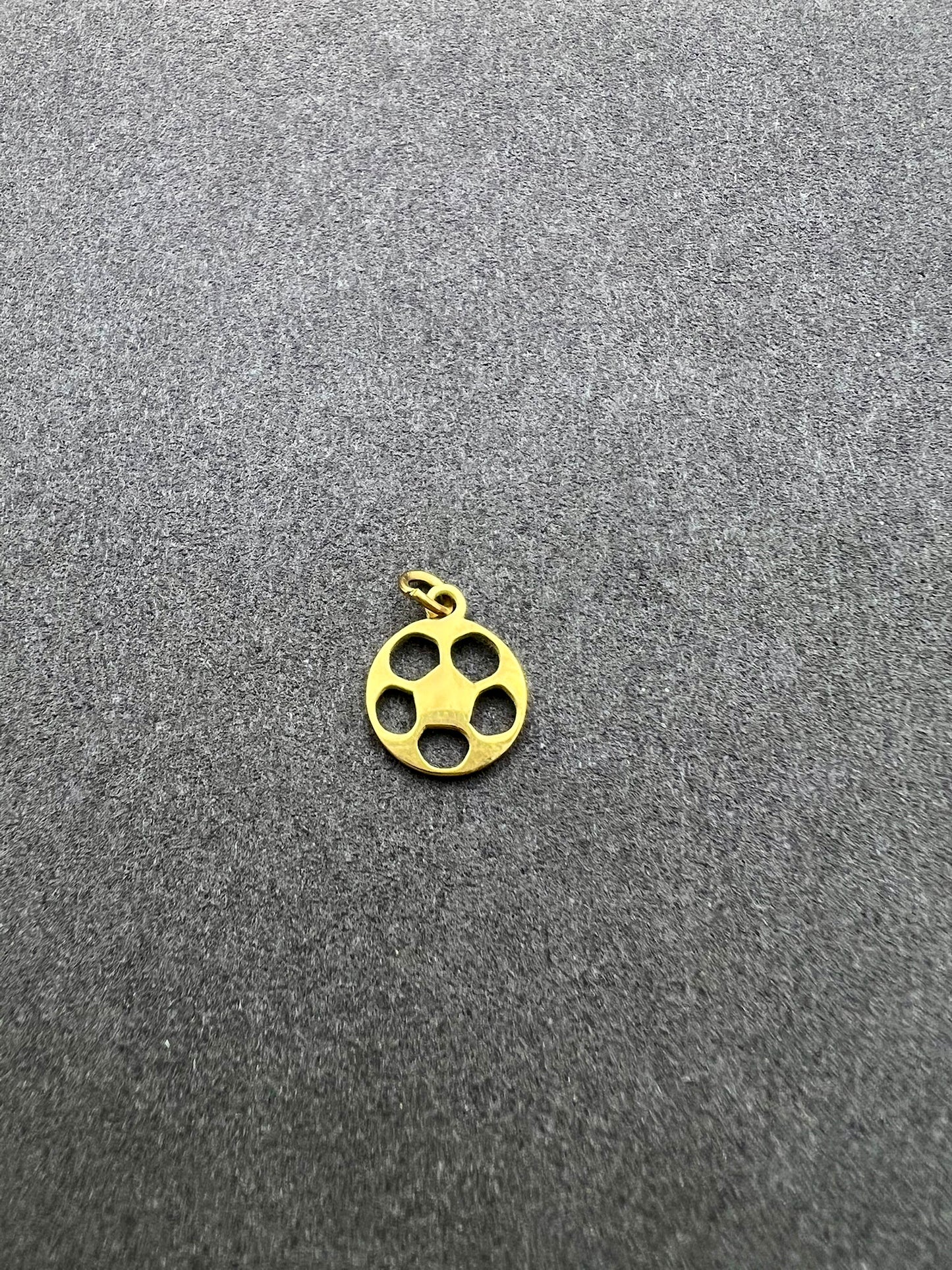 Gold pendant with four holes on a gray background