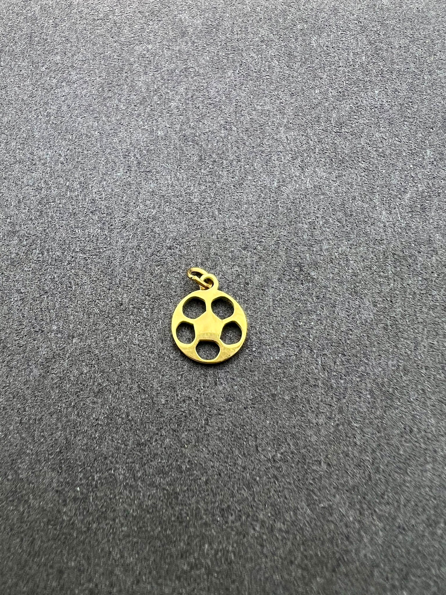Gold pendant with four holes on a gray background