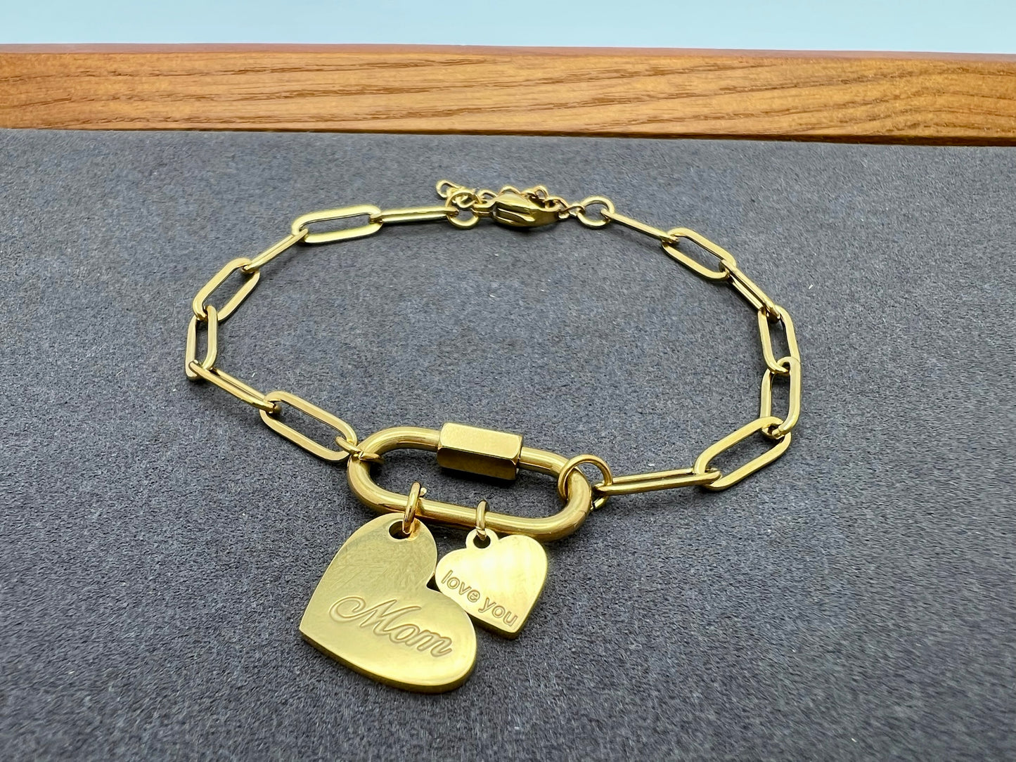 Gold chain bracelet with heart-shaped charms on a gray surface