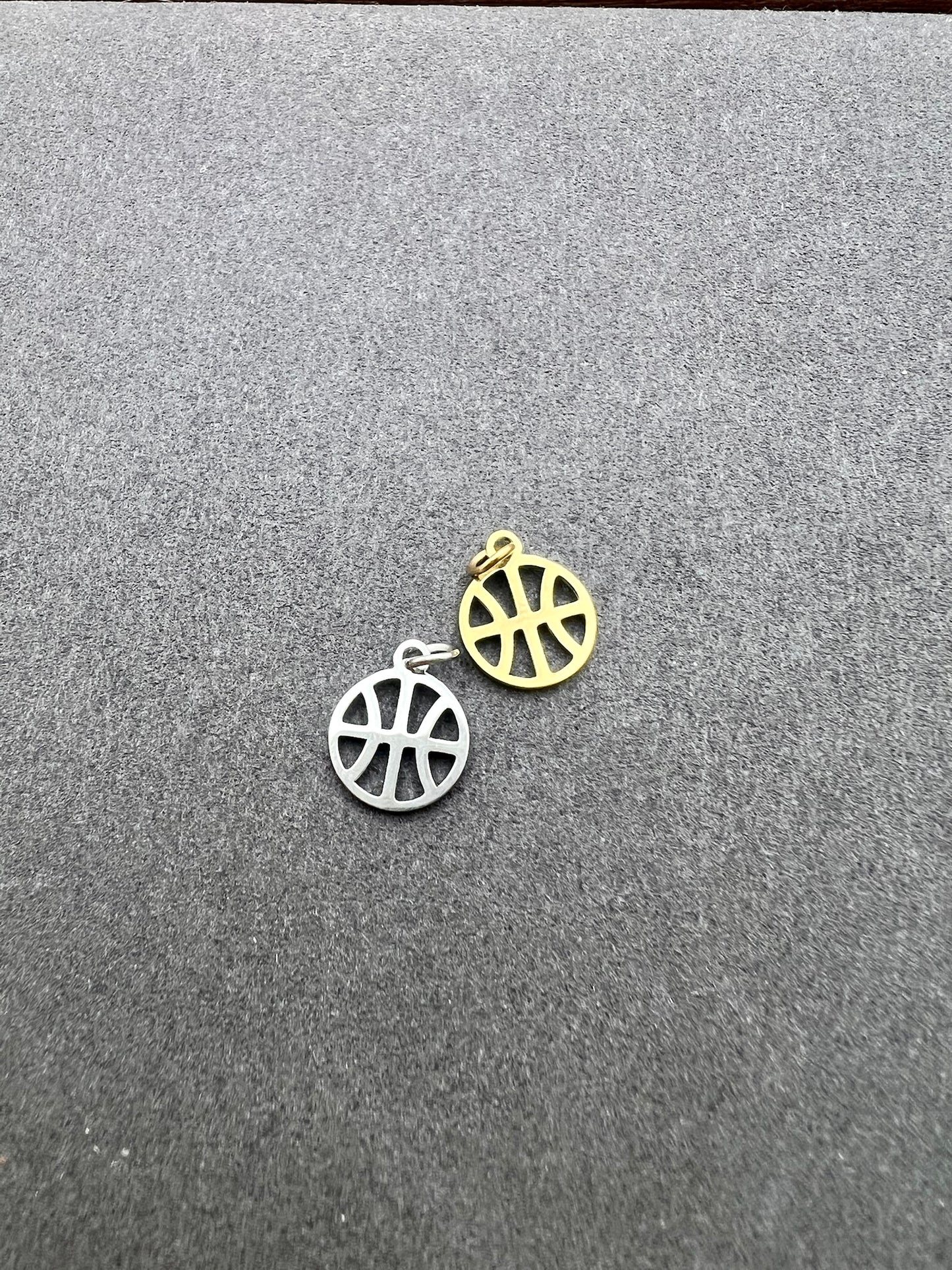 Two circular pendants, one silver and one gold, on a gray surface.