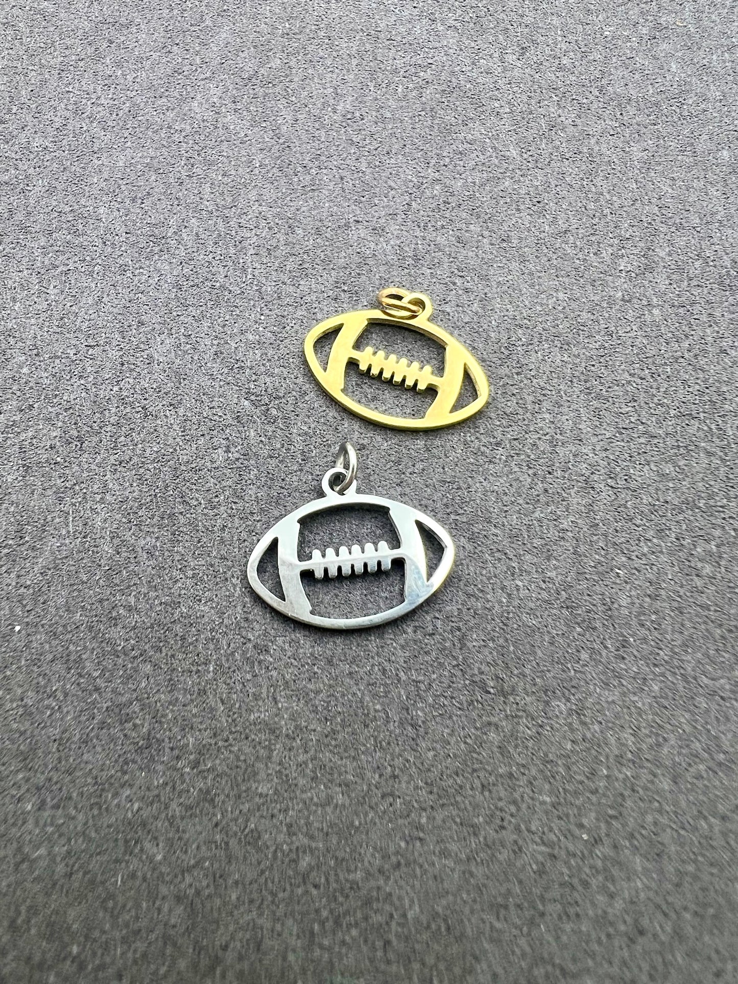 Two football-shaped charms, one gold and one silver, on a gray background.
