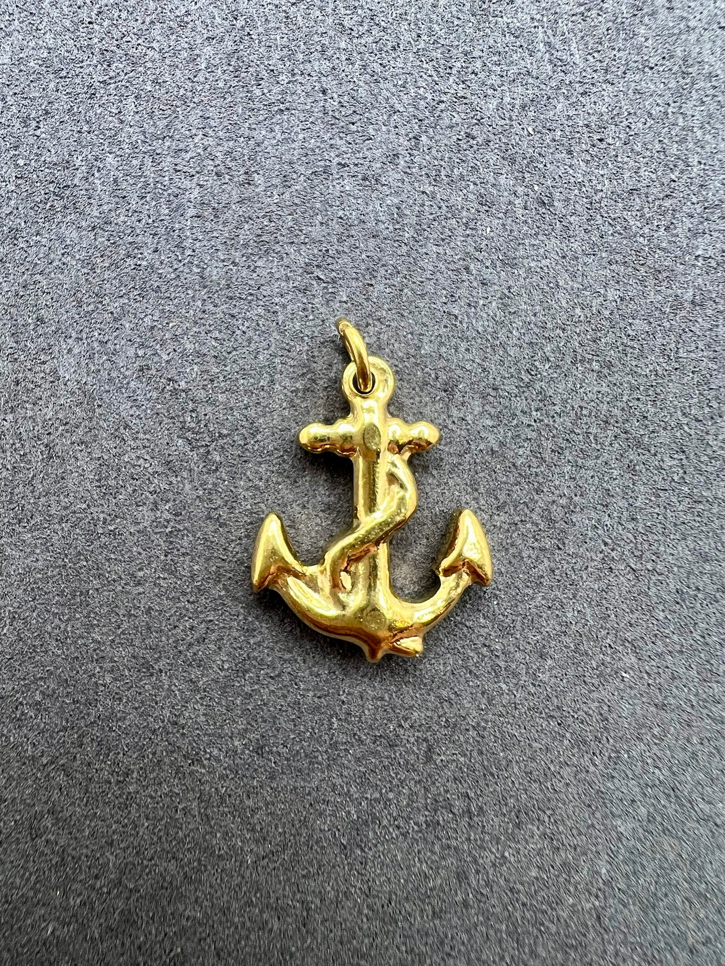 Gold anchor pendant on a gray background