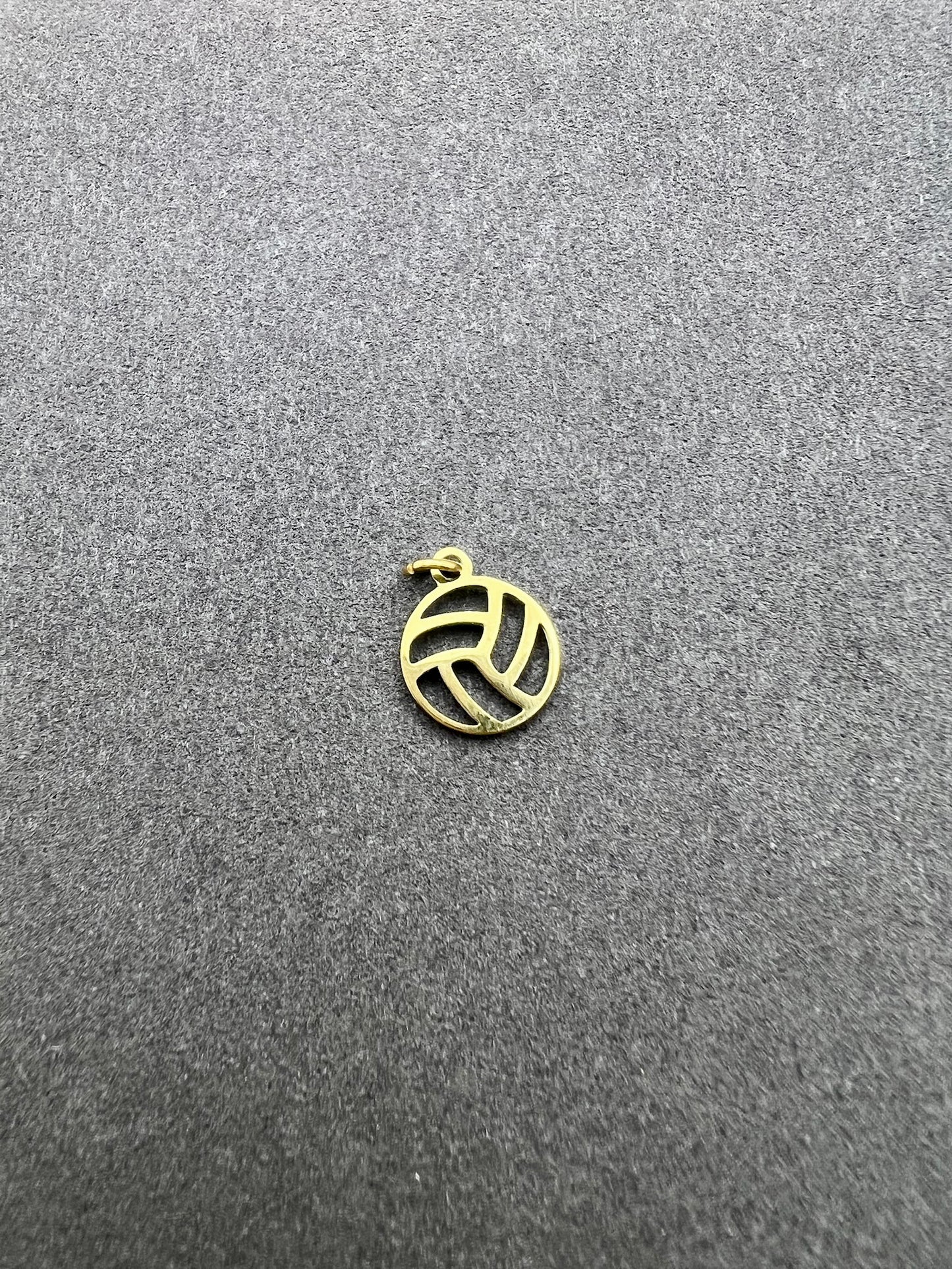 Gold volleyball charm on a gray textured background