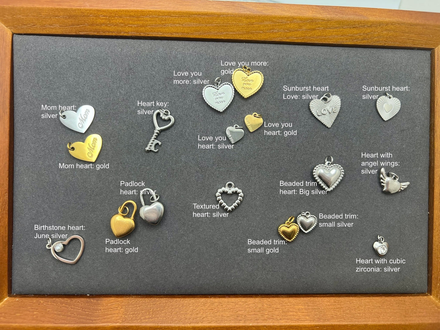 Collection of heart-shaped jewelry charms on a gray background with labels.