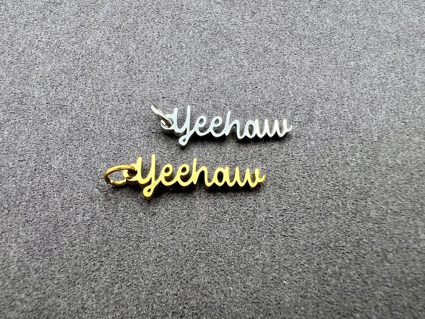 Two 'Yeehaw' metal charms on a gray textured background
